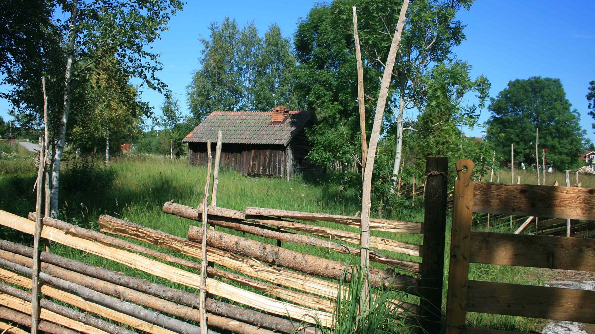 Gärdesgård framför timrat, rödfärgat hus