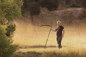 Emil V Nilsson med lie på en äng.